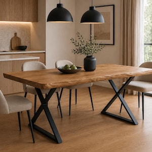 Può includere: Un tavolo da pranzo in legno con bordo naturale e gambe in metallo nero. Il tavolo è circondato da quattro sedie imbottite beige. Due lampade a sospensione nere sono appese sopra il tavolo in una cucina moderna.
