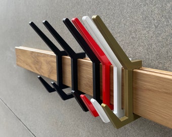 May include: Five wall-mounted hooks in different colours: black, red, white, and gold. The hooks are mounted on a wooden board.