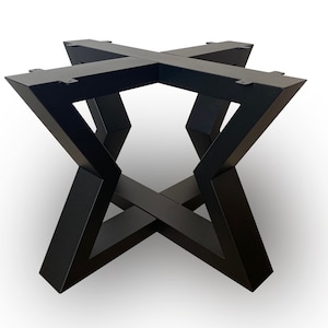 Könnte beinhalten: Ein schwarzes Metall-Tischgestell mit geometrischem Design. Das Gestell hat ein X-förmiges Design mit abgewinkelten Beinen und einer flachen Oberseite zur Befestigung einer Tischplatte. Das Gestell ist etwa 61 cm hoch.