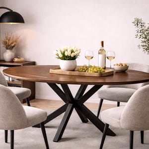May include: A round, dark wood dining table with a black metal base, surrounded by four light gray upholstered chairs. The table is set with a bottle of wine, glasses, and a tray of fruit and flowers. A floor lamp and decorative plant are in the background.
