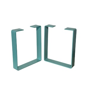 May include: Two teal-coloured, U-shaped metal table legs. Each leg has a rectangular frame with a flat top featuring pre-drilled holes for mounting. The legs are designed for supporting a tabletop and have a modern, minimalist aesthetic.