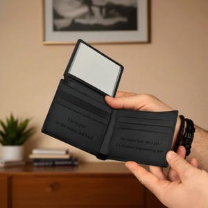 May include: Black leather wallet with a clear ID window and multiple card slots. The wallet is open, revealing the engraved text "I love you to the moon and back" and "No matter how old I get, I will never stop needing you."
