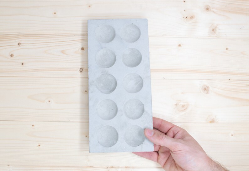 Puede incluir: Una bandeja de hormig&oacute;n gris con 12 hendiduras circulares. La bandeja est&aacute; dise&ntilde;ada para hacer peque&ntilde;as manualidades o servir aperitivos.