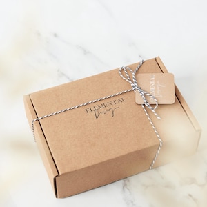 May include: A brown cardboard box with a white and black twine bow. The box is labeled "Elemental Design".