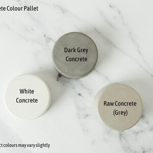 Puede incluir: Tres peque&ntilde;as muestras de hormig&oacute;n en diferentes colores: blanco, gris claro y gris oscuro. Las muestras est&aacute;n etiquetadas como "Hormig&oacute;n blanco", "Hormig&oacute;n en bruto (gris)" y "Hormig&oacute;n gris oscuro".