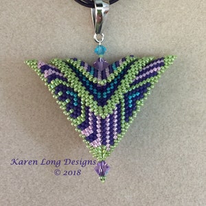 May include: A green, purple, and blue beaded pendant with a silver bail and a crystal drop. The pendant is in the shape of a triangle and has a geometric pattern. The pendant is hanging from a black cord.
