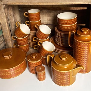 May include: A vintage brown and orange patterned tea set with a teapot, creamer, sugar bowl, cups, saucers, and plates. The set is arranged in a wooden crate.