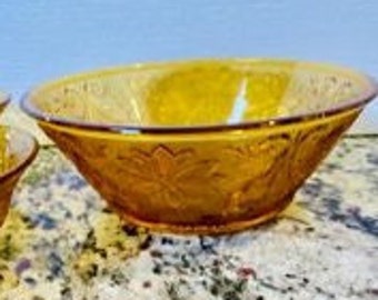 May include: A set of four amber glass bowls with a floral pattern. The bowls are nested inside each other.