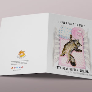 Op de afbeelding: Een kaart met een aquarel-illustratie van een kat in een wieg. De tekst op de kaart luidt: "Ik kan niet wachten om mijn nieuwe menselijke broertje of zusje te ontmoeten. P.S. De wieg die je voor me in elkaar hebt gezet is leuk."