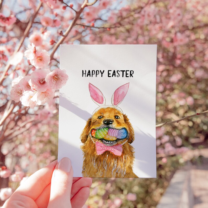 May include: A watercolor illustration of a golden retriever dog wearing bunny ears and holding a basket of Easter eggs in its mouth. The card says "Happy Easter".