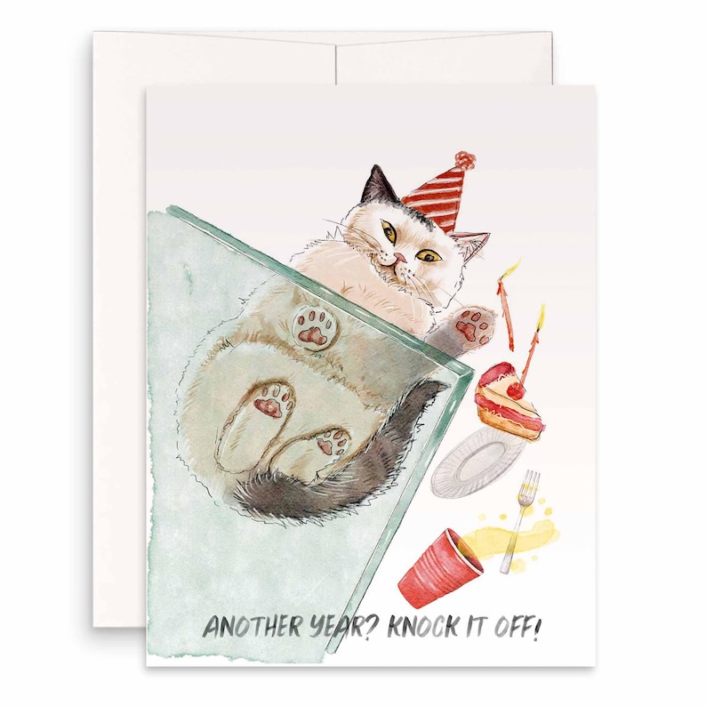 Pu&ograve; includere: Biglietto di compleanno ad acquerello con un gatto con un cappello da festa, sdraiato sulla schiena. La carta include una fetta di torta, un bicchiere rosso e il testo "ANOTHER YEAR? KNOCK IT OFF!"