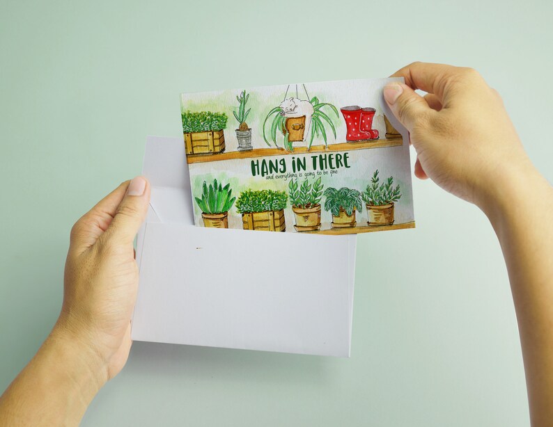 Peut inclure: Une carte de v&oelig;ux aquarelle avec une illustration de plantes en pot sur une &eacute;tag&egrave;re, en vert et marron. Le texte sur la carte est "Hang in there and everything is going to be fine."