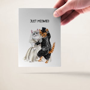 May include: A wedding card with a white cat wearing a veil and a brown cat wearing a tuxedo and top hat. The text on the card reads "Just Meowied".