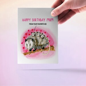 May include: A greeting card with a watercolor illustration of a possum with babies on its back. The card says "Happy Birthday Mom" and "From your favorite kid".