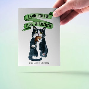 May include: A greeting card featuring a black and white cat holding a brown mouse. The card has a green ribbon with the text "Thank you for being so pawsome" and the text "Please accept my appreciation!" at the bottom.