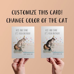 May include: A customisable birthday card featuring a cartoon cat wearing a party hat and sitting on a person's head. The card reads "Rise and Shine It's Your Birthday" and "And My 3AM Meal Time".