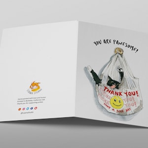 May include: A greeting card with a black cat in a white plastic bag. The bag has red text that says "Thank You!" and a smiley face. The card has the text "You are pawsome!" in black.