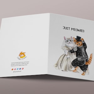 May include: A greeting card with a watercolor illustration of two cats dressed in wedding attire. The text "Just Meowed" is printed on the card.