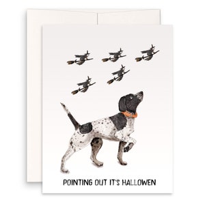 May include: A black and white dog with a brown collar is pointing upwards at five black witches flying on broomsticks. The text "POINTING OUT IT'S HALLOWEEN" is at the bottom of the card.