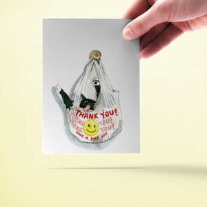 May include: A white plastic bag with a black cat inside. The bag has the text "THANK YOU!" and a smiley face printed on it.