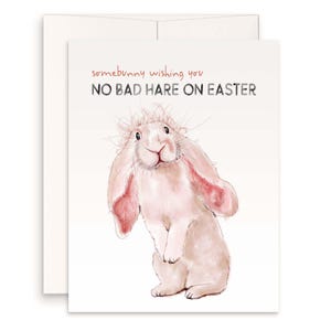 May include: Easter greeting card featuring a watercolor illustration of a pink bunny with long ears. The card reads "somebunny wishing you NO BAD HARE ON EASTER" in red and black text. The card is accompanied by a white envelope.