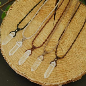 May include: Five necklaces featuring clear, pointed crystal pendants suspended on woven cord. The cords are available in black, beige, and various shades of brown, each secured with a small bead above the crystal point for a secure fit.