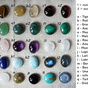 May include: A collection of polished gemstones in various shapes and colors, including tiger's eye, amethyst, and lapis lazuli. The gemstones are round (12 mm) and oval (10 x 14 mm).