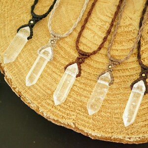 May include: Five necklaces featuring clear, faceted crystal points suspended from macrame cords in black, beige, dark brown, light brown, and deep brown. Each pendant is secured with a small metallic bead at the top of the woven cord setting.