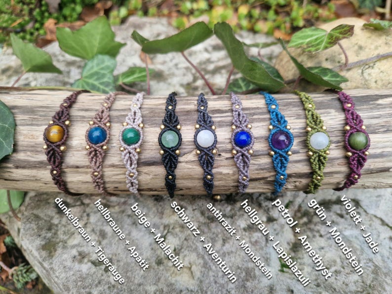 May include: A collection of handmade macrame bracelets, each featuring a central gemstone and gold-colored beads. The bracelets are in various colors, including brown, beige, black, gray, blue, green, and purple, with gemstones like tiger's eye, apatite, malachite, aventurine, moonstone, lapis lazuli, amethyst, and jade.