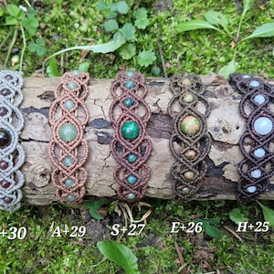 Puede incluir: Cinco pulseras de macram&eacute; con diversas cuentas de piedras preciosas, incluyendo granate, jade y unakita. Las pulseras se exhiben sobre un trozo de madera contra un fondo de follaje verde. Cada pulsera est&aacute; etiquetada con una combinaci&oacute;n de letra y n&uacute;mero.