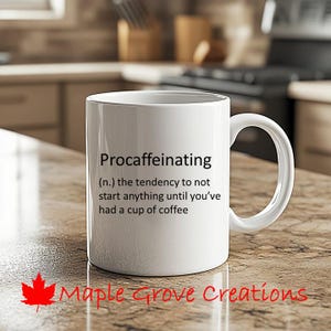 May include: White ceramic coffee mug with black text that reads "Procaffeinating (n.) the tendency to not start anything until you've had a cup of coffee".