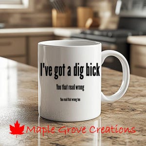 以下が含まれることがあります： 白いセラミック製のコーヒーカップで、黒い文字で「I've got a dig bick You that read wrong You read that wrong too」と書かれています。