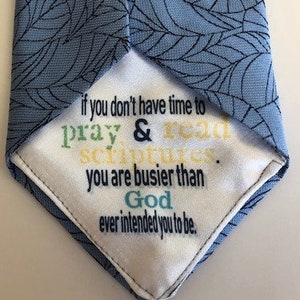 May include: A blue tie with a leaf pattern. The tie is flipped inside out to reveal a white fabric with the text "if you don't have time to pray & read scriptures, you are busier than God ever intended you to be."