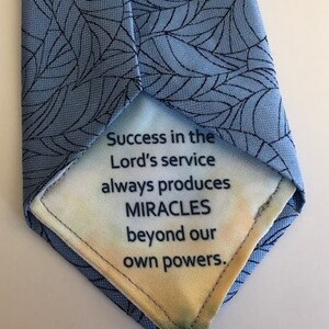 May include: A light blue tie with a black leaf pattern. The inside of the tie features the text: "Success in the Lord's service always produces MIRACLES beyond our own powers."