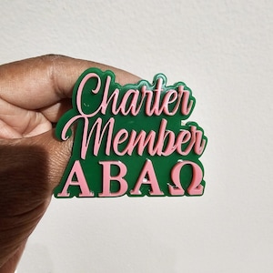 May include: Green and pink plastic pin with the text "Charter Member ABAΩ".
