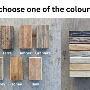 May include: A selection of wooden blocks in various colors, including black, terra, amber, graphite, light grey, honey, and raw. The text "Please choose one of the colours below" is at the top, with color names below each block.