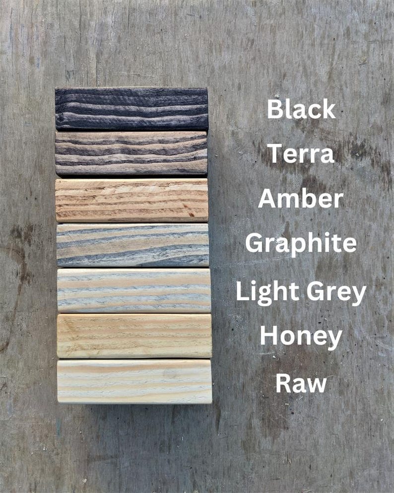 May include: A vertical arrangement of seven wooden blocks, each stained a different color. The colors are black, terra, amber, graphite, light grey, honey, and raw. The names of the colors are listed in white text to the right of the blocks.