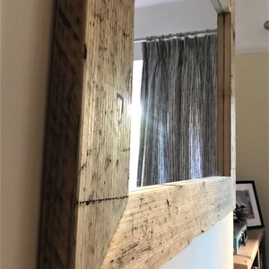 Op de afbeelding: Een grote rechthoekige spiegel met een rustieke houten lijst. De lijst is gemaakt van gerecycled hout en heeft een natuurlijke, verweerde afwerking.