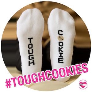 May include: White socks with the words "Tough Cookies" printed on them. One sock has the word "Tough" and the other has the word "Cookie" with a cookie graphic.