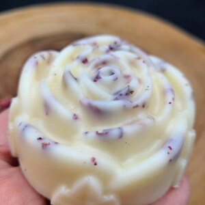 May include: A white rose-shaped soap with dried rose petals embedded in it.