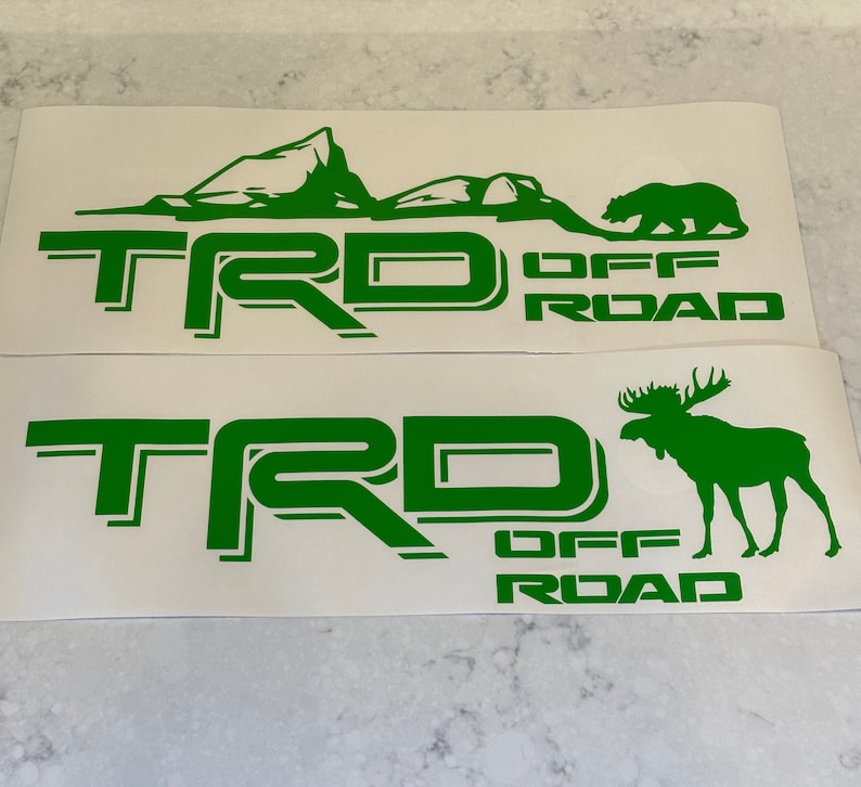 May include: Two green vinyl decals with the text "TRD OFF ROAD" and a mountain scene with a bear on the top decal and a moose on the bottom decal.