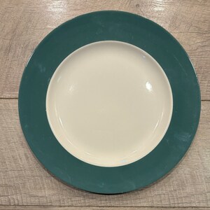 May include: A white ceramic dinner plate with a wide green rim.