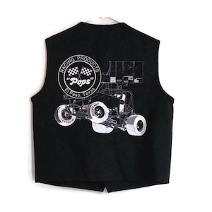 Puede incluir: Chaleco negro sin mangas con un gráfico blanco de un coche de carreras y el texto "Racing Products "Pops" El Paso, Texas" en un círculo.