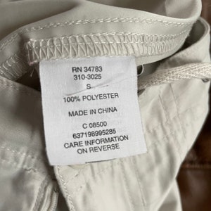 May include: White clothing tag with black text. The tag says "RN 34783 310-3025 S 100% POLYESTER MADE IN CHINA C 08500 637198995285 CARE INFORMATION ON REVERSE".