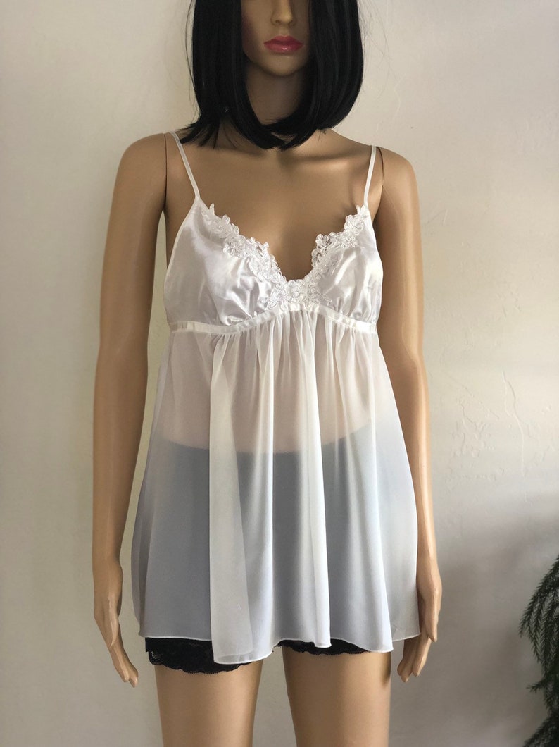 K&ouml;nnte beinhalten: Ein wei&szlig;er, durchsichtiger Slip mit einem Satin-Oberteil und Spitzenbesatz. Der Slip hat einen V-Ausschnitt und verstellbare Tr&auml;ger.
