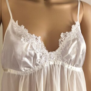 K&ouml;nnte beinhalten: Ein wei&szlig;er Satin- und Chiffon-Schlafanzug mit zarter Spitze am Ausschnitt.
