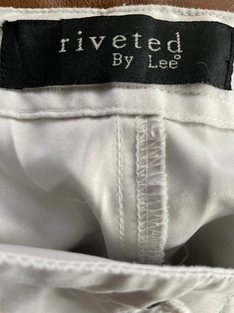May include: White pants with a black label that reads "riveted By Lee"