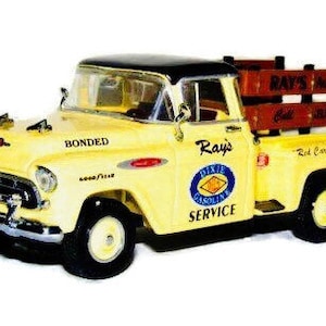 May include: A yellow toy truck with a black cab and a wooden bed. The truck has the words "Ray's Dixie Gasoline Service" and "Bonded" printed on the side. The truck is a model of a 1950s Chevrolet.