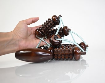 Könnte beinhalten: Ein Holz-Handmassager mit einer Reihe verbundener Rollen. Die Rollen haben eine strukturierte Oberfläche und sind durch ein blaues Band verbunden.