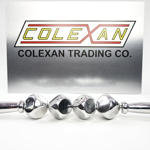 May include: A silver metal ice roller with a handle and four round, faceted, ice-cold balls. The roller is made by Colexan Trading Co.